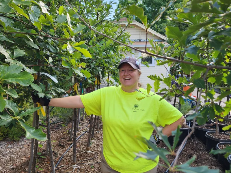 Amanda Westendorf stands facing the camera surrounded by young trees
