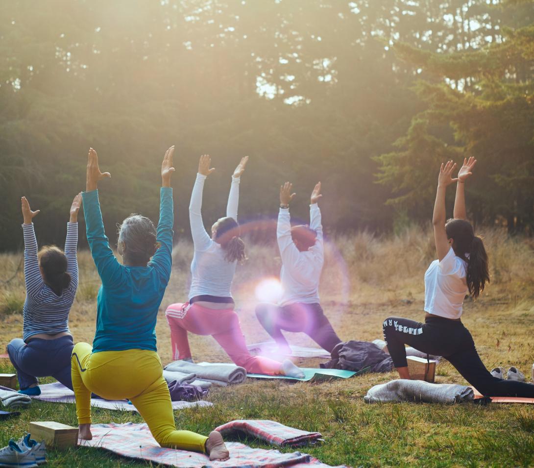 Group practicing sun salutation outdoors